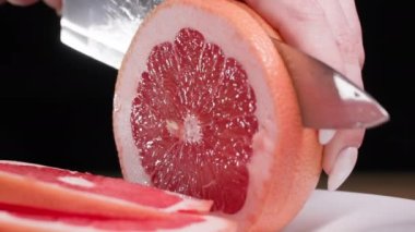 Kadın eli, nefis kokulu greyfurt kokulu koyu bir arka planda, yakın planda hiçbir şey olmadan kesilir.