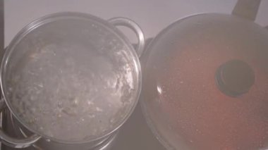 Yemek pişirme, kadın eli tencerenin kapağını açar, kaynar su ocağın üzerinde gezinir, yakın plan.