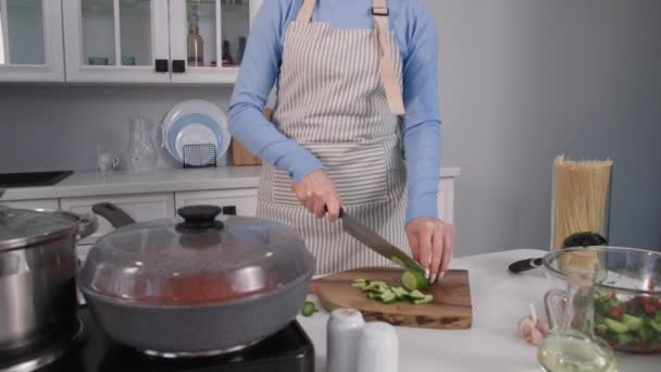 Repas sains, une jeune femme prépare des plats végétariens et coupe des légumes frais crus sur une planche à découper tout en restant debout dans la cuisine à la maison — Video