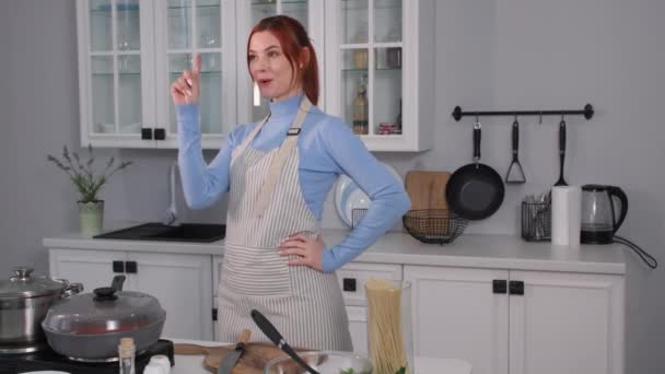 Γυναίκα αποφασίζει να μαγειρέψει ένα υγιεινό γεύμα από φρέσκα λαχανικά στη συνέχεια πιάνει μια πράσινη σαλάτα και την κόβει με ένα μαχαίρι σε ένα ξύλο κοπής, ενώ στέκεται στην κουζίνα — Αρχείο Βίντεο