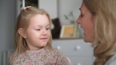 Ebeveynlerle ilişki, tatlı bir kız anne ile eğleniyor elleriyle yüzüne dokunuyor ve evde dinlenirken burnunu öpüyor, gülümsüyor ve kameraya bakıyor.
