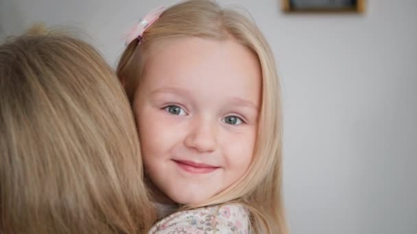 Children relationship with their parents, portrait of a cute adorable girl hugs her mom tightly, smiles and looks at the camera — Stock Video