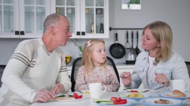 Aile yemeği, neşeli evli bir çift ve güzel bir kızı var. Mutfakta yemek yerken eğleniyorlar.