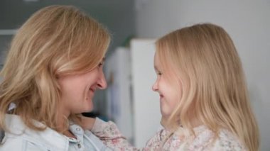 Annelik, mutlu küçük kız evde dinlenirken şefkatli annesine nazikçe sarılıyor.