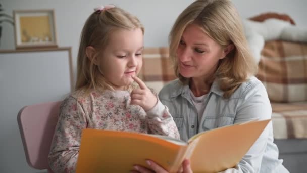 Alegre infancia, adorable preescolar hembra se divierte con la madre y toca su cara con las manos y besos nariz mientras se relaja en casa en la sala de estar — Vídeos de Stock