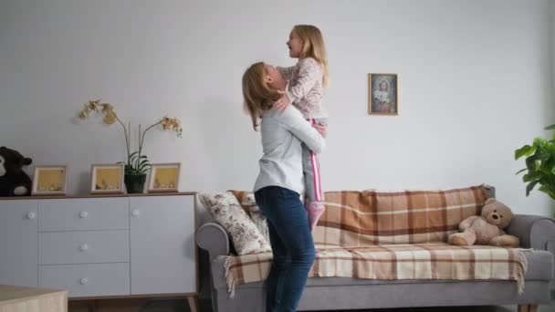 Ebeveynler ve çocuklar arasındaki ilişki, sevimli kadın ebeveyn küçük bir kızı kollarına alır ve evde dinlenirken onu döndürür. — Stok video