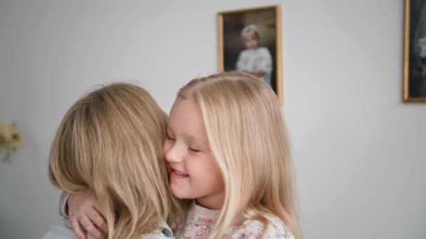 Χαρούμενη παιδική ηλικία, αξιολάτρευτο θηλυκό παιδί αγκαλιάζει στοργική μαμά της σφιχτά κατά τη διάρκεια των οικογενειακών διακοπών στο σπίτι, κοντινό πλάνο — Αρχείο Βίντεο