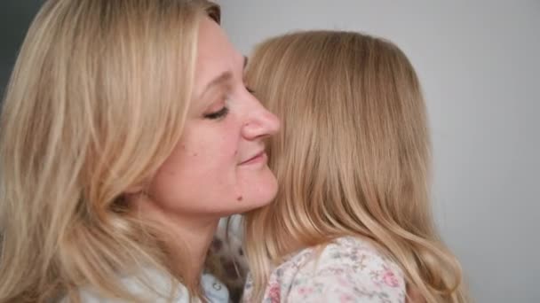 Rodičovská, milující žena láskyplně objímá svou malou roztomilou dcerku, zatímco odpočívá doma, vychutnává si chvilku, zblízka — Stock video