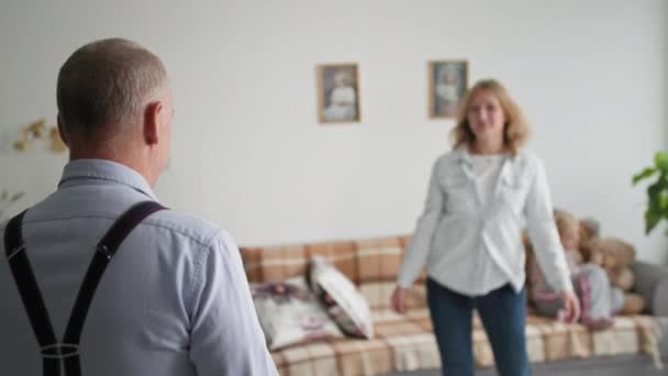 Encontro alegre, um homem adulto abraça uma mulher sorridente alegre enquanto se encontra em casa em um quarto acolhedor — Vídeo de Stock