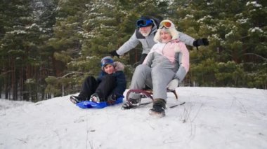 Kış aktiviteleri, sevecen büyükanne ve büyükbaba ve bir erkek çocukla birlikte ormanın arka planında kayak yaparken eğleniyorlar.