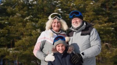 Oğlumla maç yapan mutlu yaşlı bir adam ve kadının portresi güneşli bir havada ormanda yürürken ağaçların arka planında duruyor.