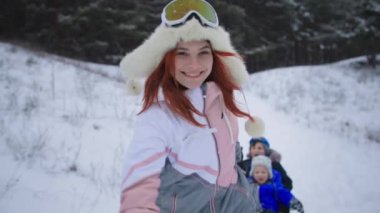 Kış tatilleri, neşeli kadın ebeveynler, sevgili oğullarının ormanda geçirdiği ortak tatilde kızakla kaymaları.