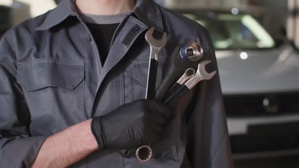 Profesjonalny mechanik samochodowy z regulowanym kluczem w ręku stoi tło samochodu w centrum serwisowym, zbliżenie — Wideo stockowe