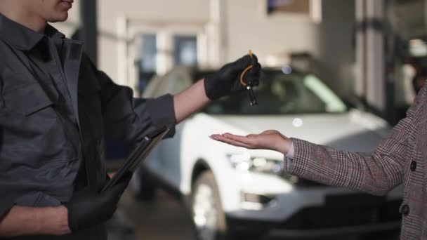 Auto service, ung kvinna ger nycklar till manlig mekaniker för bilunderhåll, närbild — Stockvideo