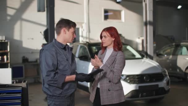 Joven cliente frustrado se comunica con un técnico masculino sobre una avería de un motor de vehículo en un servicio de coche — Vídeos de Stock