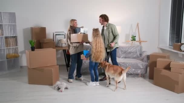 段ボール箱を持つ家族は新しいアパートに移り住むことを喜んでいます子供と犬のカップルは家で互いに5を与えます — ストック動画