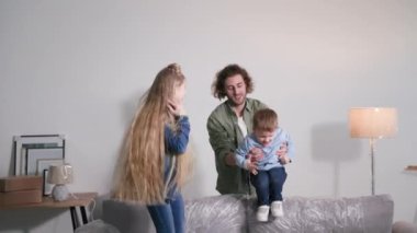 Taşınmak, çocukların karton kutularla dolu bir odada neşeli, genç bir babanın yanında plastik ambalajla kaplı bir kanepeye atlaması.