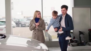 Araba almak, küçük çocuklu mutlu bir aile bayilikte yeni bir araca bakmak.