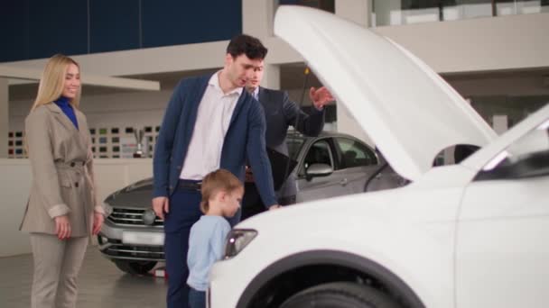 自動車事業妻と息子を持つ若い夫が新車を選ぶ車の販売代理店のマネージャーと相談する — ストック動画