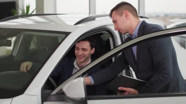 自動車販売 成功した男は自動車センターで新しい自動車を購入することについてマネージャーと話す — ストック動画