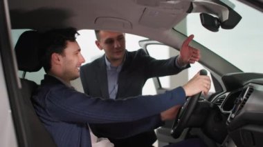 Otomobil satış merkezinde yeni arabayı otomobil satıcısıyla birlikte denetleyen başarılı bir erkek müşteri.