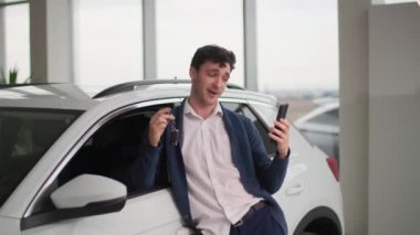 Adam otomobil galerisinde alışveriş yaparken seviniyor. Araba galerisindeki video kaydının erkek sahibi.