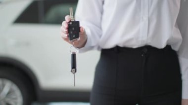 Araba galerisi, kadın otomobil satış müdürü elinde otomobil anahtarı, yakın plan.