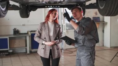 Araba servisi, tamirci adam tablet kullanır ve müşteri kızına asansörde araba tamir ederken yapılan işi açıklar.