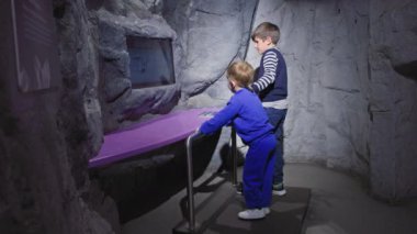 modern games, boys jump on earthquake simulator and watch on monitor impact force into room