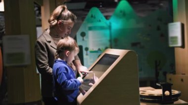 child education and development, caring male parent helping son through modern learning method on touch screen in museum