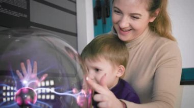 interactive toys, smiling mother plays with her son with a Tesla coil, creating electric waves, science and development