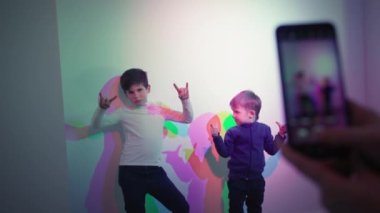 color illusion, male children posing for a photo on a mobile phone against a background of mixed colors