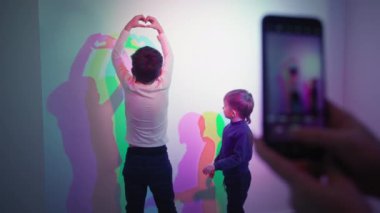 science and education, brothers pose for a photo on a smartphone against a background of mixed colors in a science museum for children