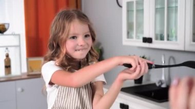 İlişki annesi, önlüklü kadın çocuk mutfakta kaşık savaşı oynarken annesiyle eğleniyor.