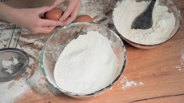 Küçük kız, anne ve kız çocuğuyla birlikte yemek pişiriyor. Genç bir kadınla birlikte yumurtaları buğday ununa dönüştürüyor. Yakın plan.