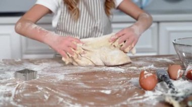 pastries, cute smiling child kneading dough from wheat flour for baking buns at home in kitchen