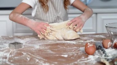 pastries, smiling child kneading dough from wheat flour for baking buns at home in kitchen