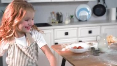 happy pastime, joyful girl cheerfully runs around kitchen while making homemade flour cookies at home