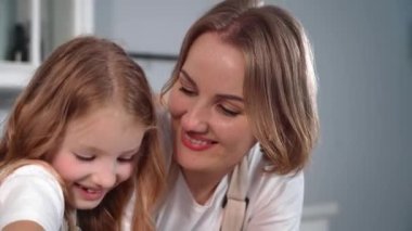 parent-child relationship, loving mother gently teaches female child to bake wheat flour buns at home against backdrop of kitchen