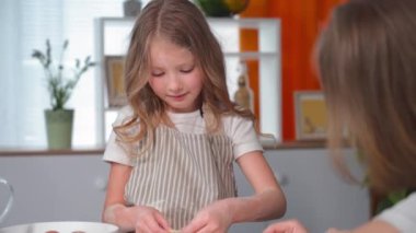 pastries, adorable female child cooks dough bagels together with mom using cookie cutter in kitchen at home