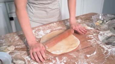 home baking, little joyful girl runs to mother to help roll out dough with rolling pin for wheat flour cookies in kitchen
