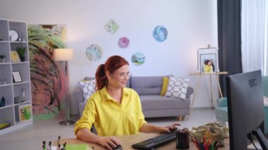 Kadın tasarımcının portresi. Ayakkabıları güncellemek, gülümsemek ve kameraya bakmak için bilgisayarda çizim yaparken eğleniyor.