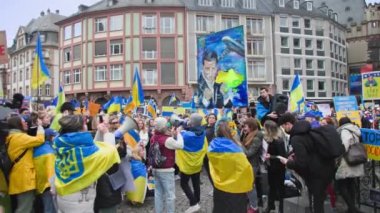 FRANKFURT AM MAIN, ALMAN- 10 Nisan 2022: Sarı-mavi bayraklı ve Ukrayna Cumhurbaşkanı Volodymyr Zelensky 'nin portresi olan insanlar Rusya ve Putin politikalarını protesto ederek Avrupa' dan yardım istediler.