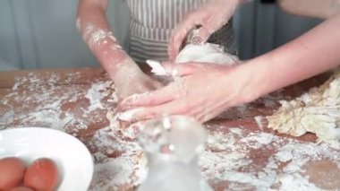 Ebeveynlere yardım et, sevimli küçük kız annesine kek ya da çörekler için mutfak masasına hamur hazırlamada yardım et, yakın plan.