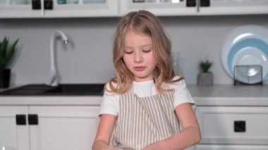 Kadın çocuk yemek yapmayı öğreniyor, elinde hamurla küçük kız mutfakta buğday ekmeği pişiriyor.