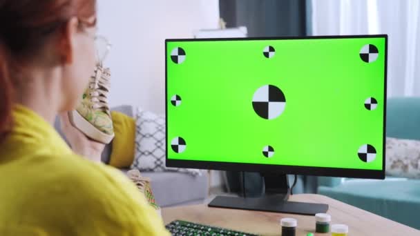 現代的なデザインの女性は机に座りながらデザインを更新するファブリックマーカー付きの緑の画面の塗装スニーカーでデスクトップコンピュータで作業しています — ストック動画