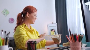 Moda projesi, kadın tasarımcı evde bilgisayar başında otururken kumaşa keçeli kalemle modern bir baskı çiziyor.