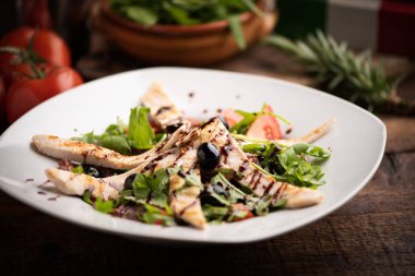 Beyaz tabakta tavuk göğsü ve taze salata.