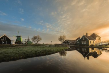 Zaanse Schans köyünde mavi gökyüzüne karşı küçük tahta köprüsü olan geleneksel yeşil Hollandalı evi. Hollanda Hollanda