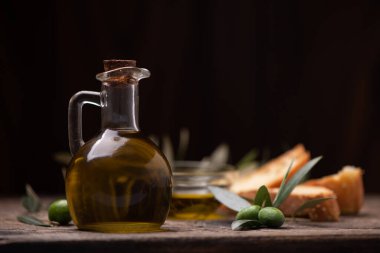 Ahşap arka planda dalları olan zeytinyağı.